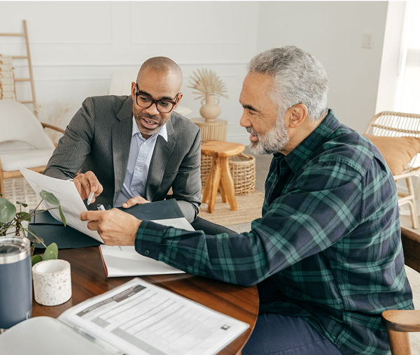 Two men discussing documents at table.